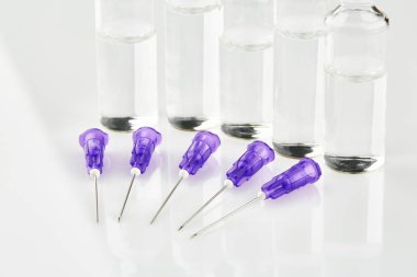 Ampul ve menekşe şırınga iğneleri beyaz arka plan üzerinde.