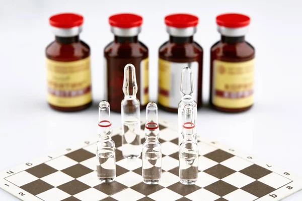 Ampoules on chess board, bottles with medicine.