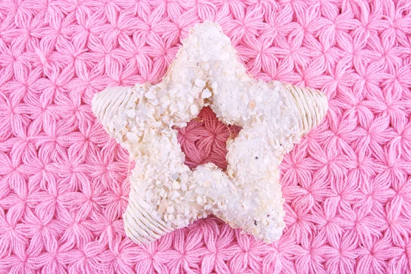 Pembe örgü peçete üzerinde yıldız şekilli Noel ağacı süsle.