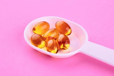 Kahverengi şeffaf kapsüller ile Plastik kaşık. Morina-karaciğer yağı