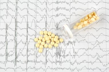 Close-up photo of yellow pills and vial on EKG graph clipart