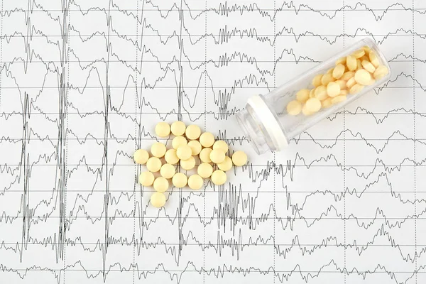 Foto de close-up de comprimidos amarelos e frasco para injetáveis no gráfico EKG — Fotografia de Stock