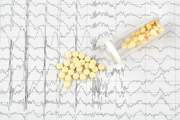 Nahaufnahme von gelben Pillen und Fläschchen auf ekg-Grafik Stockfoto