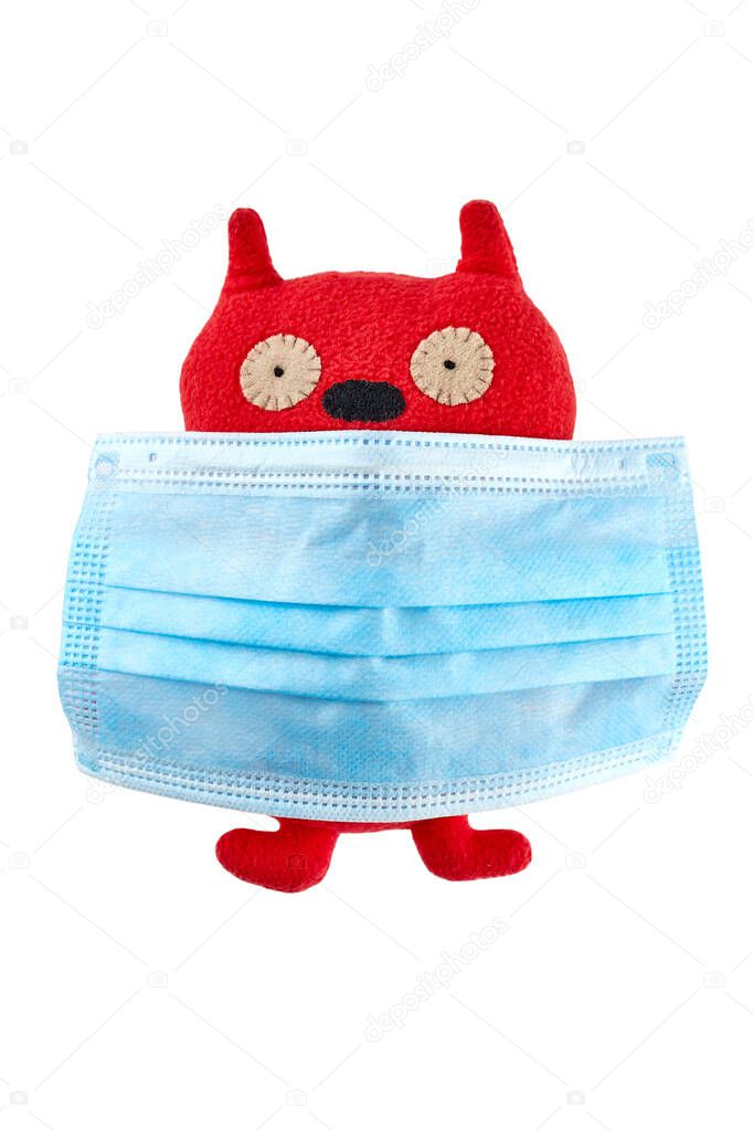 Blue medical face mask on red plush toy isolated on white background.