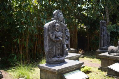 Miniature stone carvings in the form of worshipped gods are displayed outdoors in a theme park for educational purposes.