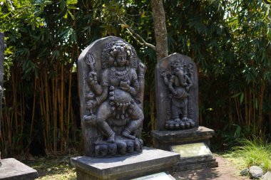 Miniature stone carvings in the form of worshipped gods are displayed outdoors in a theme park for educational purposes.