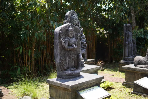 Miniature stone carvings in the form of worshipped gods are displayed outdoors in a theme park for educational purposes.