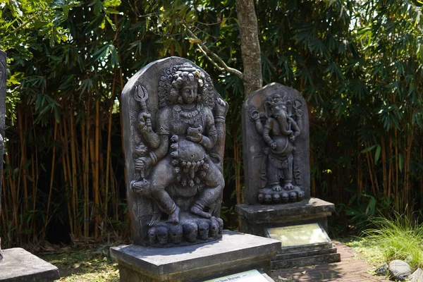 Miniature stone carvings in the form of worshipped gods are displayed outdoors in a theme park for educational purposes.
