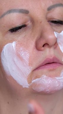 Güzellik kızı yüzüne masaj serumu yapıyor. Çekici kadın evde rutin rutinine nemlendirici krem sürüyor. Huzurlu genç bayan kameraya bakıyor cilde gençleştirici kozmetik sürtünüyor..