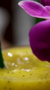 Sağlıklı tatlılar konsepti. Tahta bir masada servis edilen bardaktaki tropik chia pudingi. Arkada çiçekler var. Yüksek kalite 4k görüntü