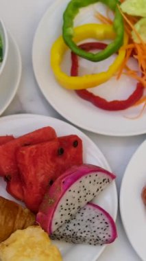 Açık hava kahvaltısı taze meyve, hamur işi, meyve suyu, kahve ve salata ile ahşap masaya yayılmış. Sabah güneşi. Bahçe manzarası. Rahatlama, yemek, sağlıklı yaşam tarzı konsepti. Yüksek kalite 4k görüntü