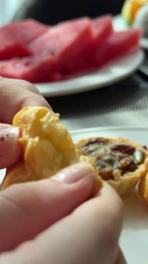 Bir kadın bir masada oturuyor. O, sütlü kahve içecek, kremalı choux pasta ve tatlı çilek yiyecek. Yüksek kalite 4k görüntü