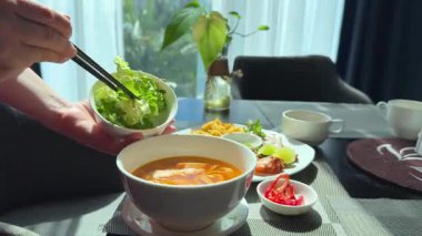 Çorbaya marul yaprağı ekle yemek masasının üzerine kadın eli ve Vietnam yemek çubukları ile fosfor çorbası yap. Yüksek kalite 4k görüntü