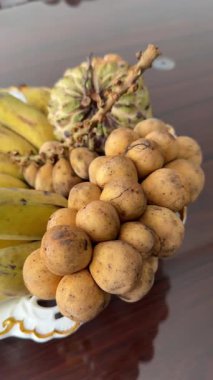 Langsat meyvesiyle elini soyan birinin yakın plan bir fotoğrafı. Langsat meyvesi olarak da bilinen ev yapımı Lancia meyvesi.