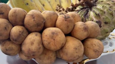 Langsat meyvesiyle elini soyan birinin yakın plan bir fotoğrafı. Langsat meyvesi olarak da bilinen ev yapımı Lancia meyvesi.