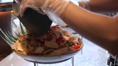 Yavaş çekimde tavukları beyaz kasede taze salataya koyan Sezar Salatası hazırlığı. Yüksek kalite 4k görüntü