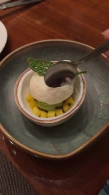 Erimiş mango dondurması damlacıkları çiçeklerle süslenmiş. Şehvetli Şefkat, Lezzetli Tatlı, Rahatlama ve Zevk Konsepti. Yüksek kalite 4k görüntü