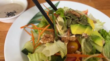 Yeşillikli avokado havuçlu sağlıklı diyet vejetaryen salatası. Elmalar yemek çubuklarını masaya koyar. Yüksek kalite 4k görüntü