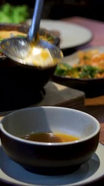 Kırsal kesimdeki düğün resepsiyonunda büyük bir tencereden portakal çorbasını kaseye döken bir adam. Yüksek kalite 4k görüntü