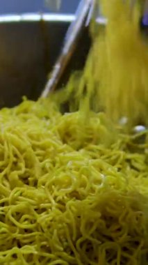 4K çözünürlükte buharlı ve dumanlı lezzetli erişteler koyu arka plan, Asya yemeği yakın plan, sıcak yemek ve fast food konsepti. Yüksek kalite 4k görüntü