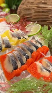 Japon suşi tabağından bir dilim ton balıklı sashimi. Stüdyo ışıkları altında siyah bir arka planda somon, deniz tarağı, yumurta ve garnitürle. Yüksek kalite 4k görüntü
