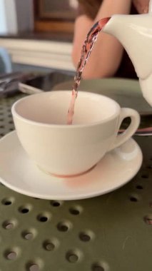 Kırsal tarzda bir çay partisi. Çaydanlıktan porselen fincana çay dökülüyor. Sabah kahvaltısı. Yüksek kalite 4k görüntü