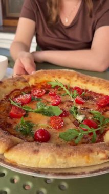 Hamur tabağı pizzacıda müşterilerin dikkatini çekerek masanın üzerinde yatıyor. Kiraz domatesli ve roka yeşili özel pizza hızlı atıştırma olanağı sağlar. Yüksek kalite 4k görüntü