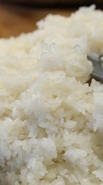 Bu video, mutfak tezgahındaki paket kutusundan alınmış pilavı kepçeleyen plastik bir kaşığın üst görüntüsünü gösteriyor. Yüksek kalite 4k görüntü