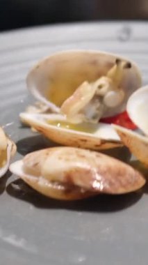 Mavi arka planı ve bir kase midyesi olan beyaz bir tabak. Midyeler öyle bir sıralanmış ki sanki tencerede gibi görünüyorlar. Yüksek kalite 4k görüntü