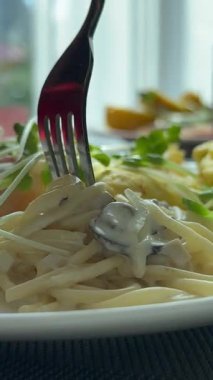 Kadın parkta makarna yiyor, sütunların yanında ya da fıskiyenin kenarında oturuyor. Retro güneş gözlüklü kız İtalyan tarzında dışarıda poz veriyor. Dikey video, aç kadın hazır. .