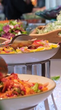 Dikey ekran kadını zarif açık büfe masasında taze salatalar sunuyor. Canlı sebzeler, rahat dekorasyon, yemek atmosferi sağlıklı yemek çeşitleri, leziz yemekler, doğal dokular..