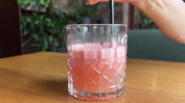 Kadın meyve sıkacağını renkli arka planda cama dolduruyor, turunçgiller kafede sağlıklı taze meyve suyu, sabah kahvaltısı içeceği. Yüksek kalite 4k görüntü