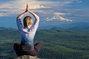 Mindfulness and inner peace. Outdoor yoga. Woman meditating by the view of volcano Mount Hood in Oregon. The Dalles.  Portland. Or. United States of America. clipart
