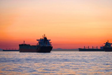 Kargo gemisi günbatımında okyanusta. Vancouver Adası yakınlarında Pasifik Okyanusu. Victoria. British Columbia. Kanada.