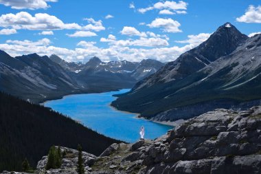 Vacation travel in Canadian Rockies in summer. Woman   on mountain top above Spray lake. Popular West Wind Tower hiking trail. Canmore. Kananaskis. Alberta. Canada. clipart