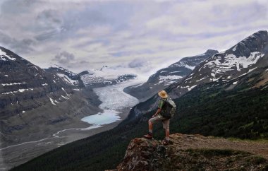 Columbia Icefield buzul ve buzultaş göl üzerinde dik uçurumdaki maceracı adam uzun yürüyüşe çıkan kimse. Banff fırtınada yaz / Jasper Milli Parkı. Kanada Rocky Dağları. Patterson Ridge iz. Alberta. Kanada.