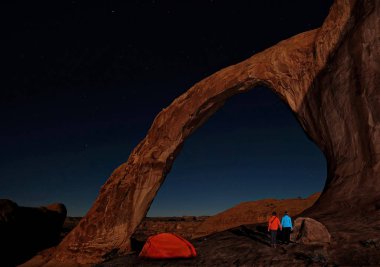 Kamp çadır ve evli çift manzarayı doğal kemer ve yıldızlar geceleri. Kumtaşı Corona kemer Utah Moab yakınındaki bir rock çölde. Amerika Birleşik Devletleri.