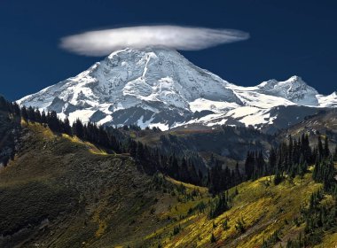 Lenticular cloud over snow capped mountain. Beautiful Mount Baker with a cloud on its top on a clear and colorful autumn  day. Mount Baker National Forest in  North Cascades Mountains. Pacific Northwest. Washington. USA clipart