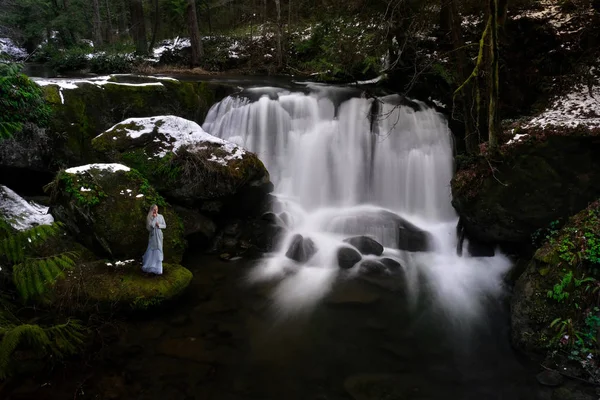 Woman by waterfall in winter forest. — Stock Photo, Image