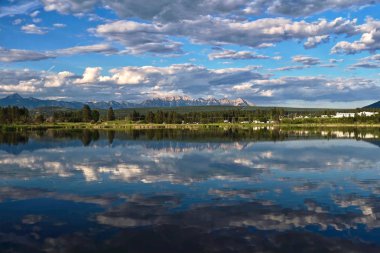 Bir yaz gününde sakin suda küçük bir köy ve dağların güzel yansıması. Kootenay Nehri ve Kanada Rocky Dağları tarafından tatil kabin ve kır evleri. İngiliz Kolombiyası. Kanada
