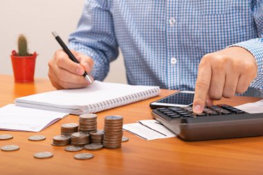 Ödeme faturalarını listelemek için kalem kullanan adam. Calulator 'a bir işaret daha. Ödeme kredi kartı.