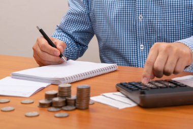 Ödeme faturalarını listelemek için kalem kullanan adam. Calulator 'a bir işaret daha. Ödeme kredi kartı.