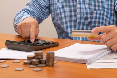 Hesap makinesi kullanarak kredi kartı ödeyen bir adam. Ödeme kredi kartı. Ödeme faturaları kredi kartıyla.