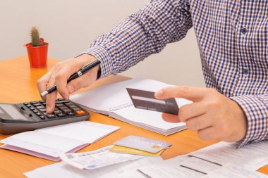 Hesap makinesi kullanarak kredi kartı, vergi ve kredi kartı ödeyen bir adam. Kredi kartı, kredi kartı.