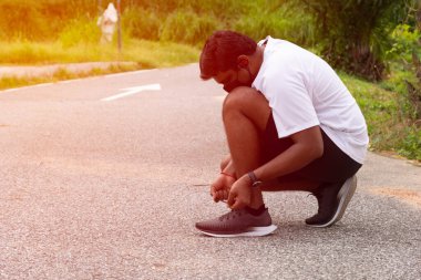 Beyaz gömlekli genç ve çekici bir adam. Koşu ayakkabılarını fotokopi aletiyle bağlıyor.