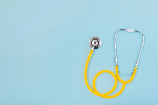 Sarı steteskop mavi arkaplanda izole edilmiş ve metin için kopyalama alanı var.