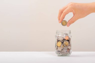 Beyaz adam, altın sikkeyi kavanozun içine koymak için tutuyordu ya da beyaz arka planda biriktirmek için cam şişeyi. Para biriktirme, tasarruf kavramı