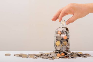 Beyaz adam, altın sikkeyi kavanozun içine koymak için tutuyordu ya da beyaz arka planda biriktirmek için cam şişeyi. Para biriktirme, tasarruf kavramı