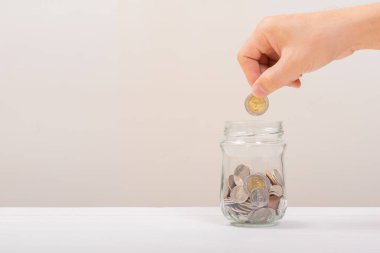 Beyaz adam, altın sikkeyi kavanozun içine koymak için tutuyordu ya da beyaz arka planda biriktirmek için cam şişeyi. Para biriktirme, tasarruf kavramı