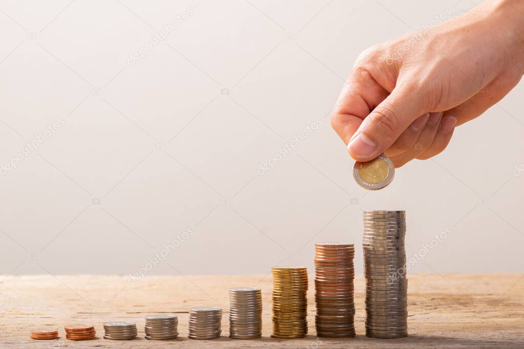 Hand putting coins on stack on table,Saving money concept or Business Growth concept